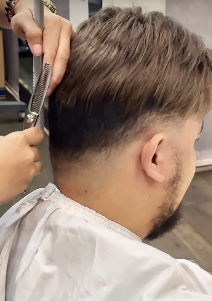 HEADS stylist blending a men's hair system into his own hair at the nape