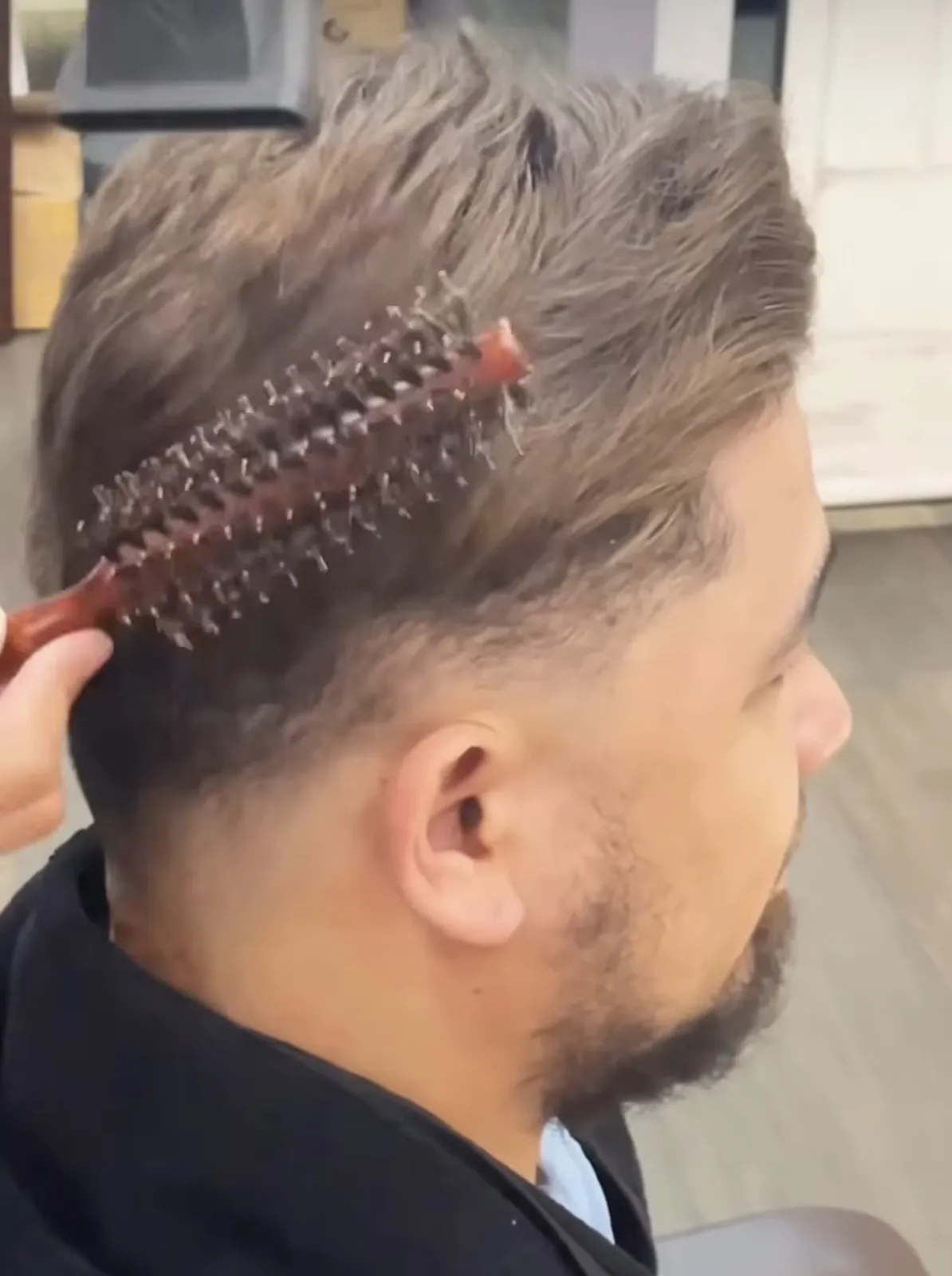HEADS stylist blending a men's hair system with a round brush